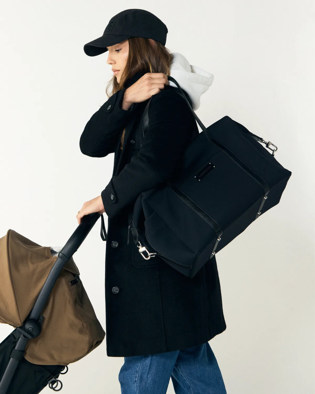 Mulher de boné preto carregando a bolsa Landucci no ombro enquanto empurra um carrinho